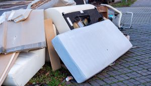 A heap of furniture and assorted belongings placed on the sidewalk.